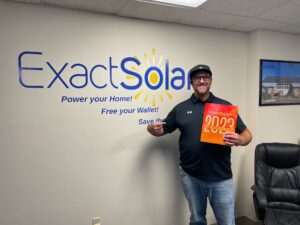 Exact Solar employee holding a copy of the Solar Power World magazine smiling next to the Exact Solar logo