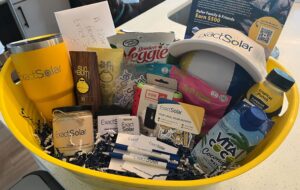 Yellow basket with dozens of branded swag items like a Yeti, hats, sunscreen, and more