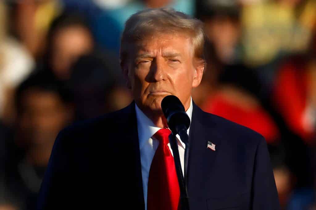 President Trump standing behind a microphone, speaking to a crowd