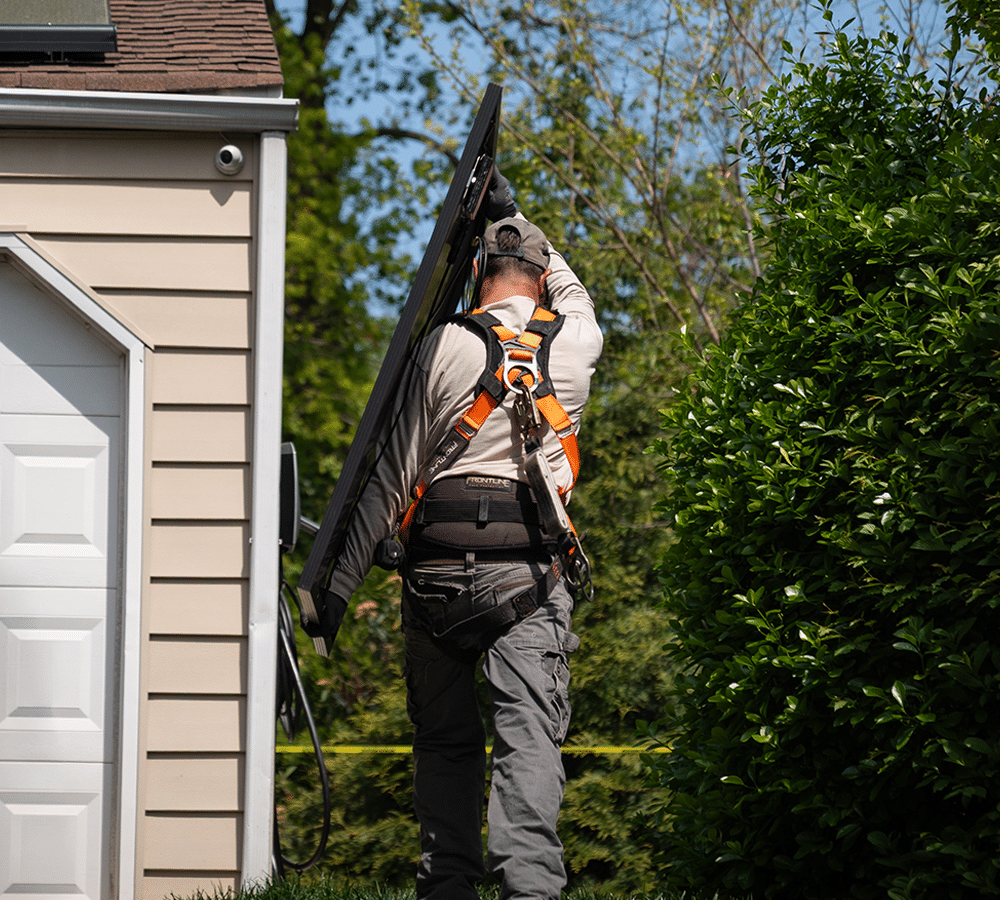 Exact Solar installer carrying a solar panel in front of a customer's home