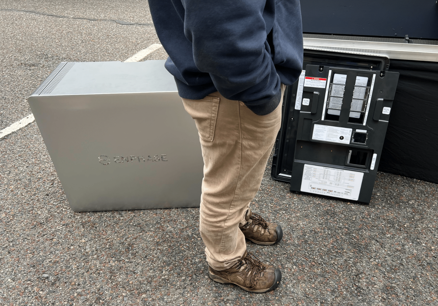 Enphase IQ 10C Battery pictured with person in foreground for size comparison.